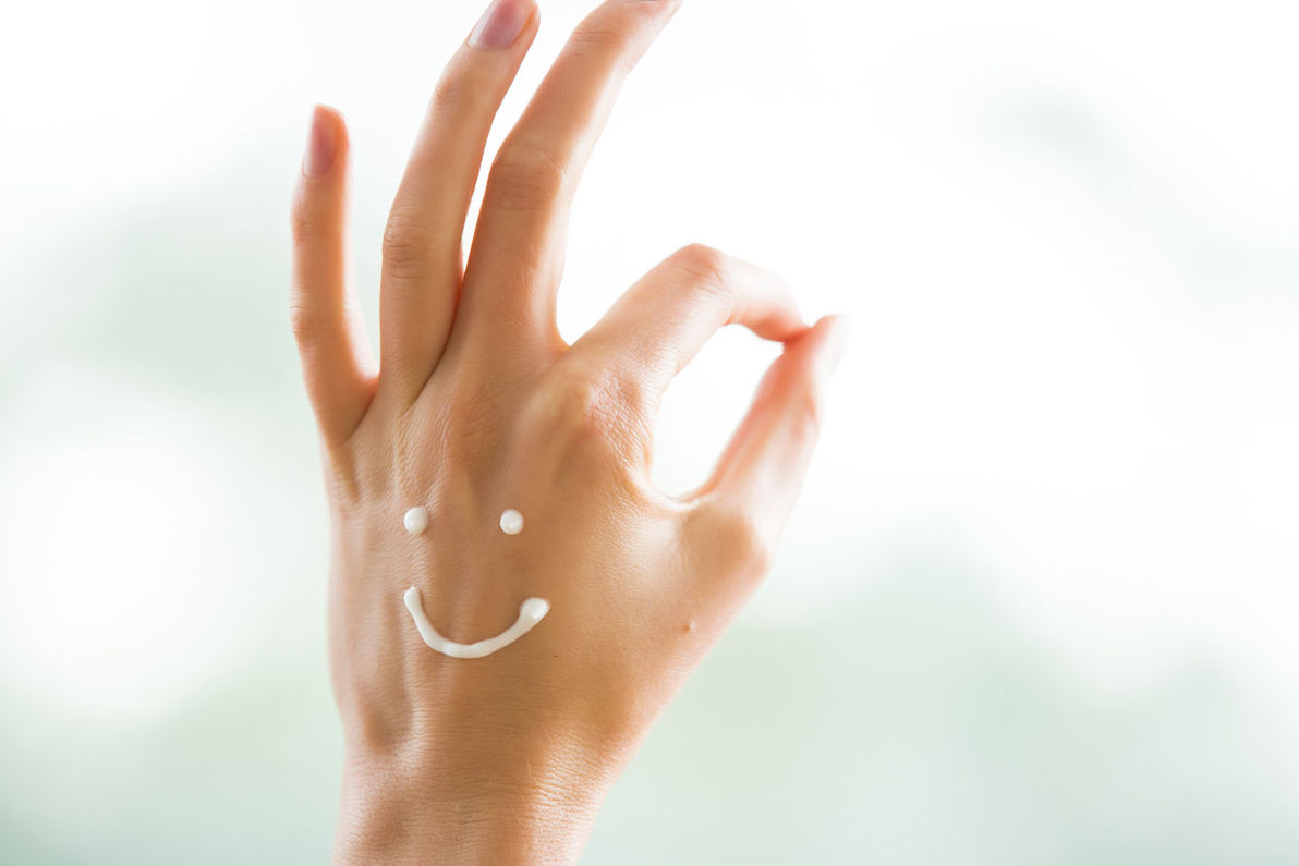Creme Smiley auf Hand, die "top" zeigt